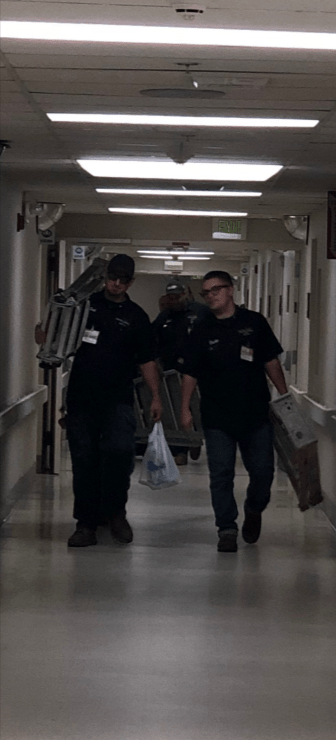 Two Certified Plumbing of Brevard plumbers walking down the hall carrying ladders in a hospital.